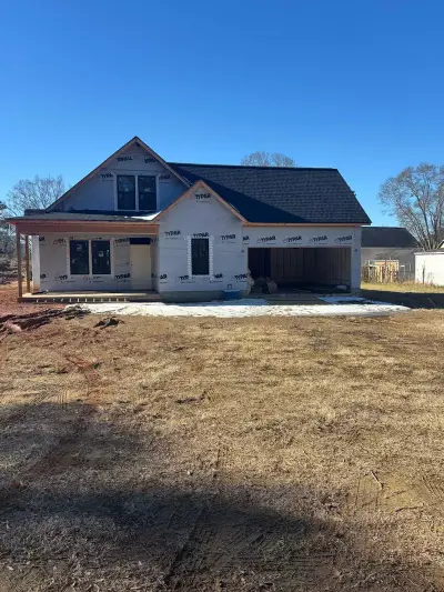 Front exterior of a newly completed two-story home with cream siding and a black roof