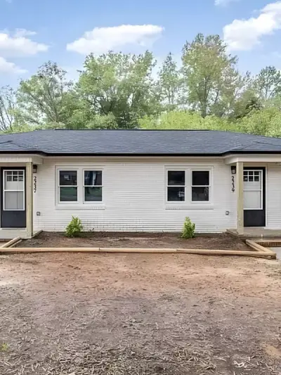 Renovated single-story duplex exterior with fresh siding, trim, and entry doors